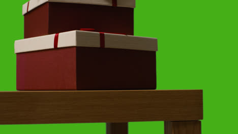 Close-Up-Of-Gift-Wrapped-Present-Boxes-On-Table-Shot-Against-Green-Screen